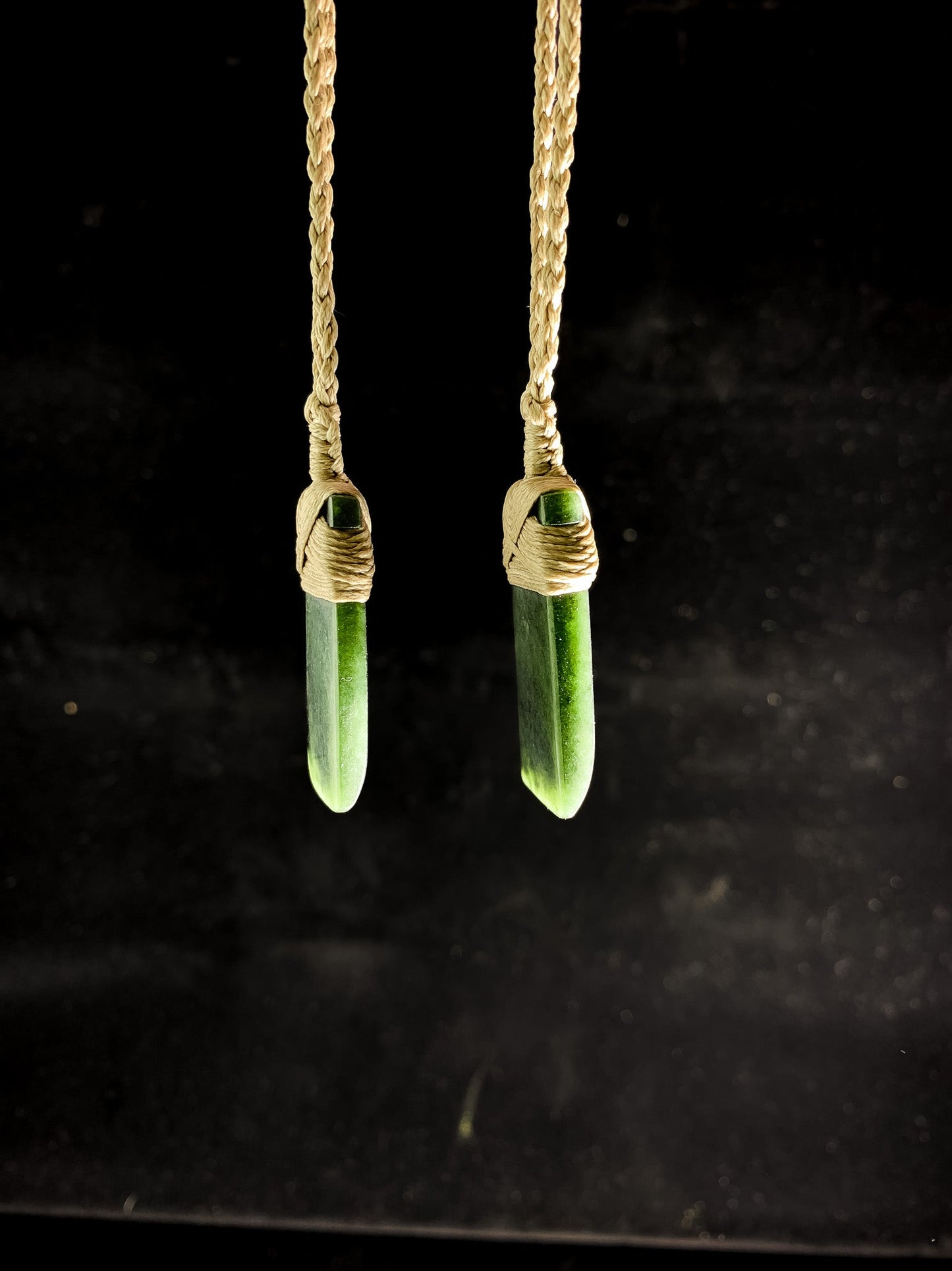 Pounamu Two Identical Hei Toki pendants on plain background