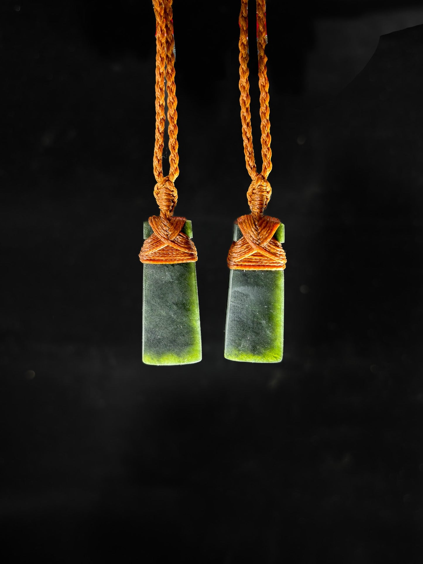 Pounamu Two Identical Hei Toki pendants on plain background