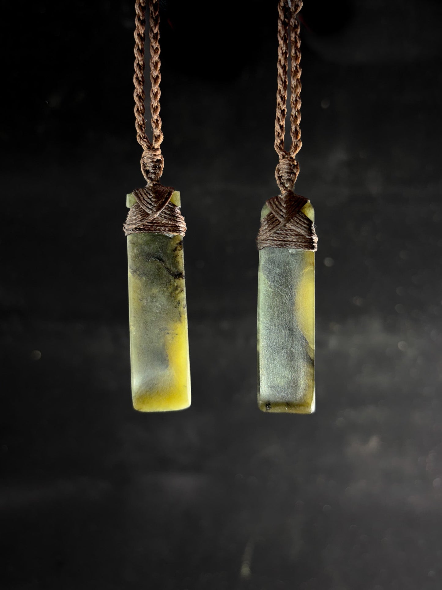 Pounamu Two Identical Hei Toki pendants on plain background