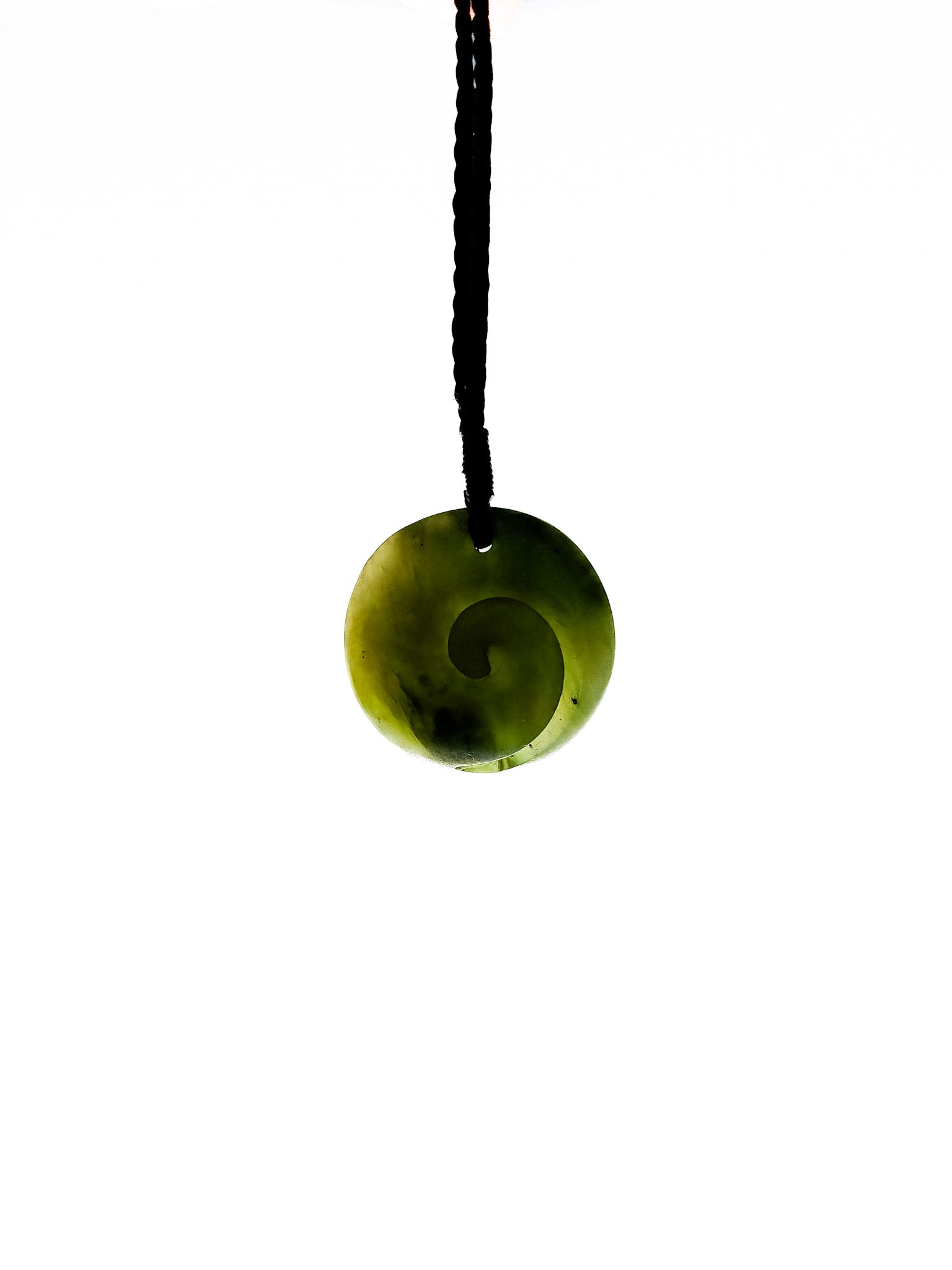 Backlit Pounamu Koru pendant on white background